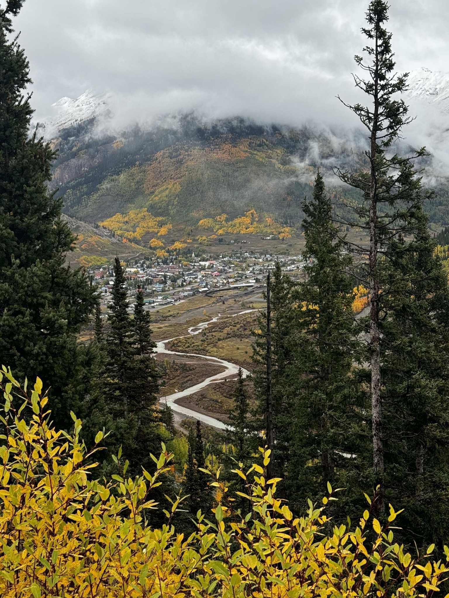 A view of a small town in the mountains surrounded by trees.