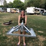 A woman is holding a large metal object in a field.