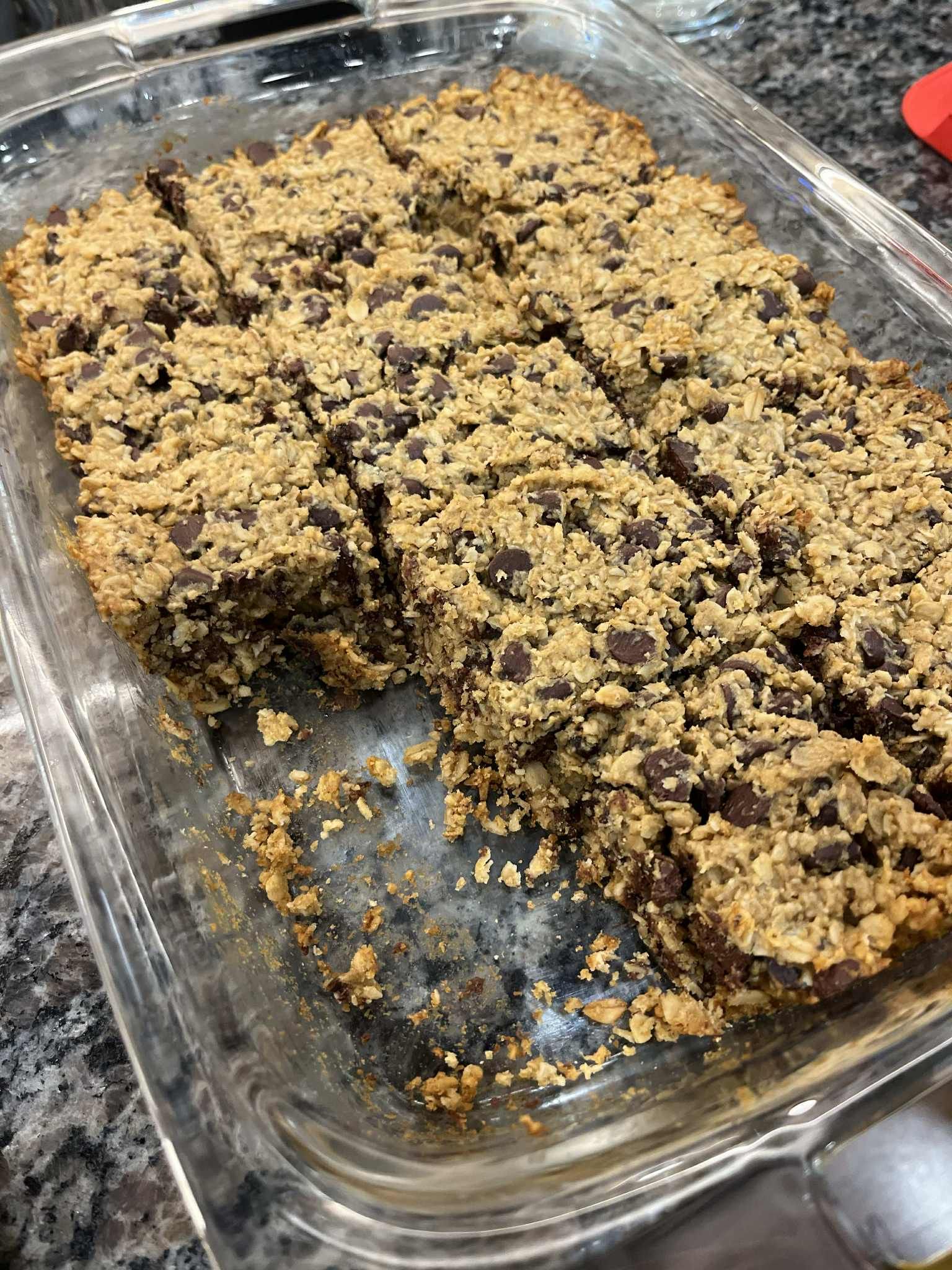 Baked dessert with chocolate chips cut into squares in a glass pan.