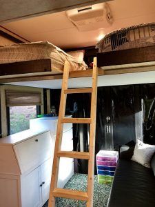 A bedroom with a bunk bed and a ladder.