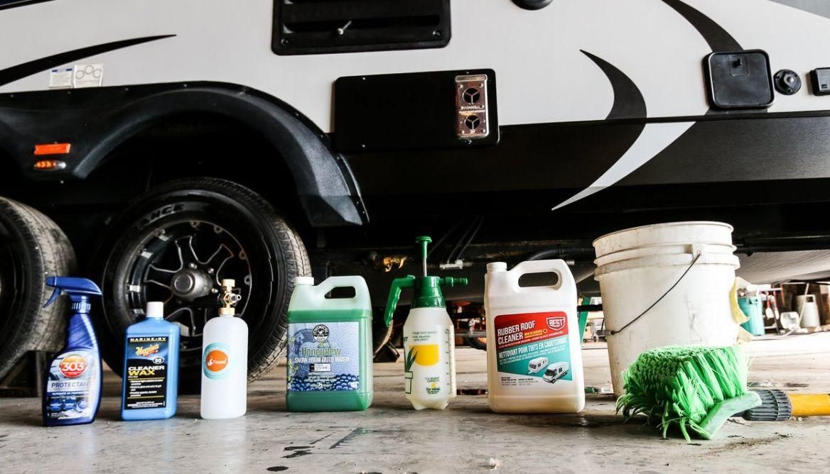 A row of cleaning supplies are lined up in front of a rv.