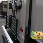 Rear of a camper with ladder and cargo carrier; light gray exterior, black accents.