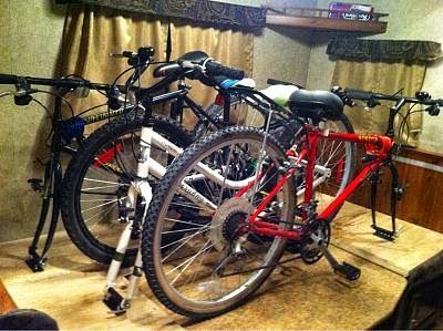 Three bicycles secured inside a camper. One is red, one white, and one black.