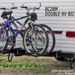 Two bikes mounted on a black RV bike rack attached to a trailer.