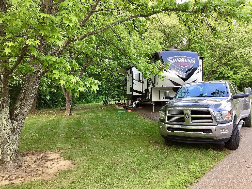 A truck is parked next to a rv in a park.