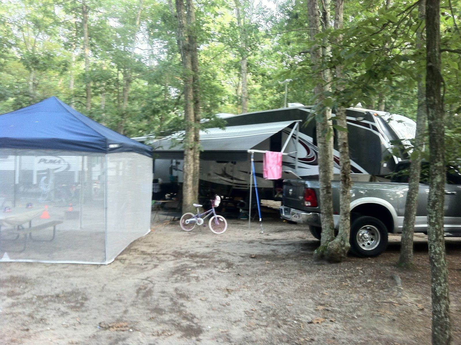 A truck is parked next to a tent and a trailer.