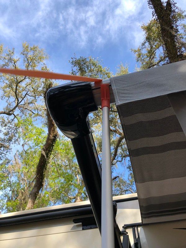 A striped awning is hanging from the roof of a rv.