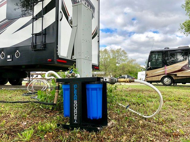 A rv is parked in a grassy field next to a water filter.