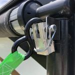 A green strap is hanging from a hook on a pole.