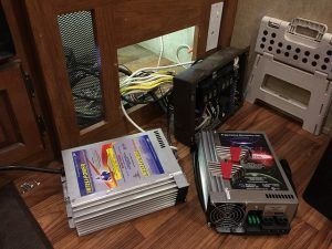 A power inverter is sitting on a wooden floor next to a cabinet.