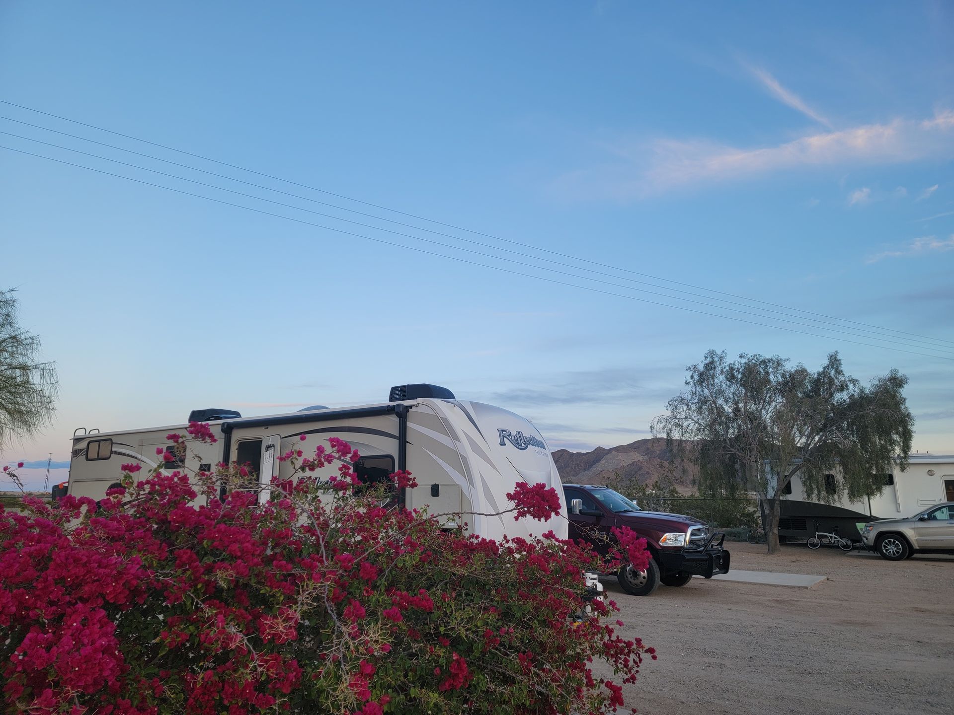 A purple truck is parked next to a rv in a parking lot.