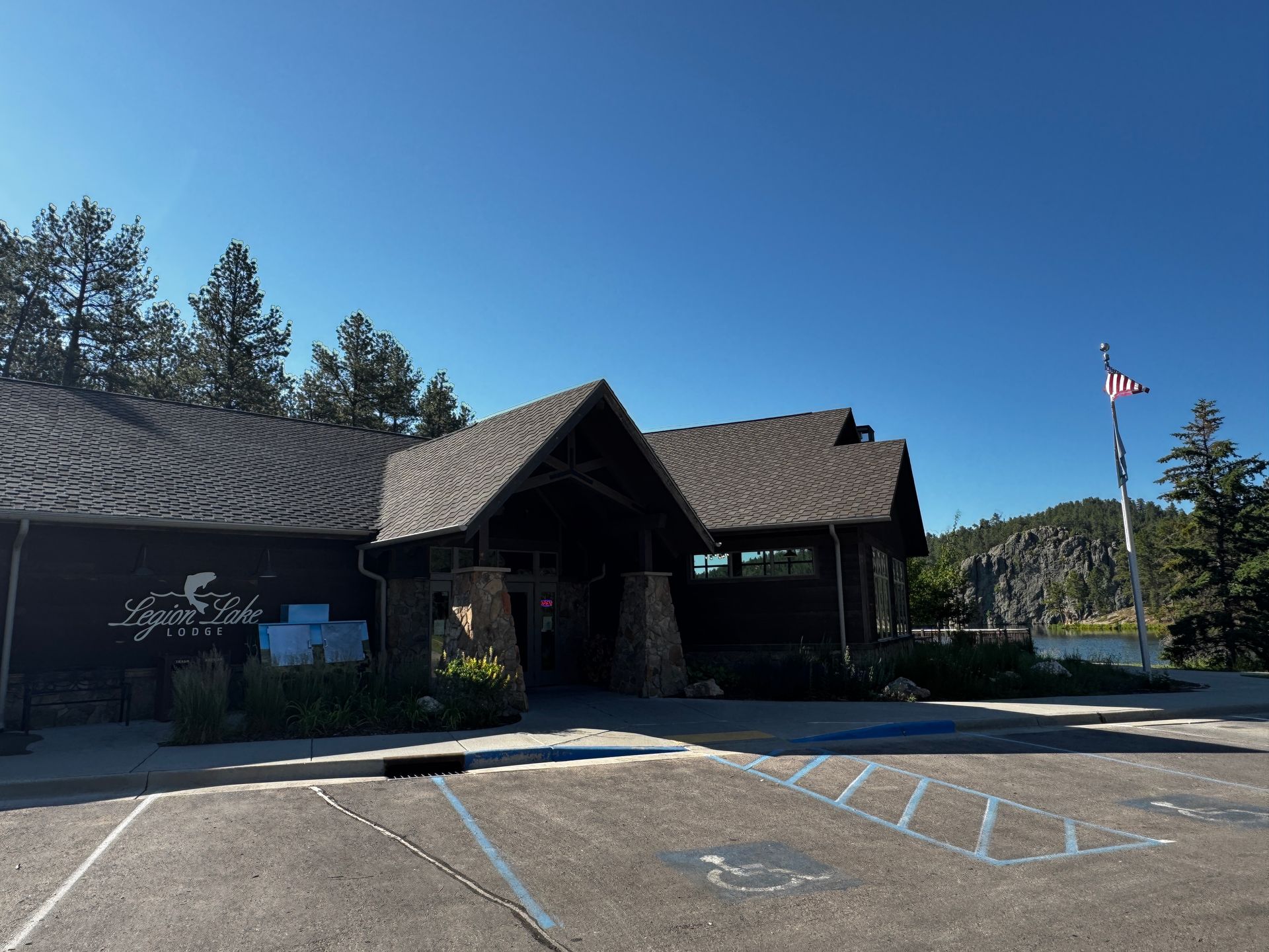 Brown building with stone accents, under a blue sky. Sign reads “Spruce Lake Lodge.”