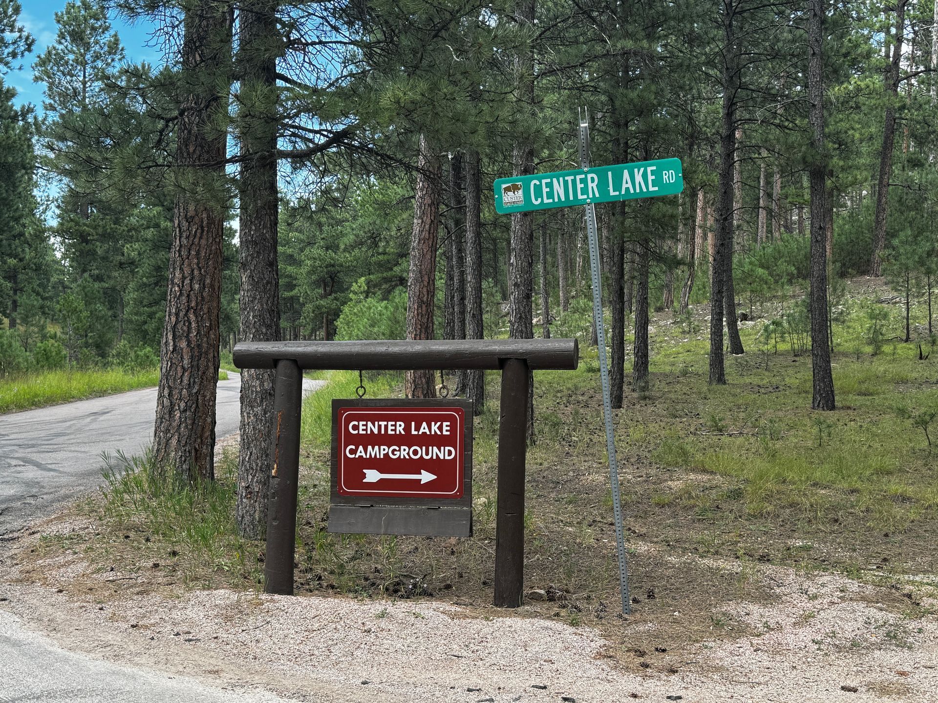 Sign for Center Lake Campground on Center Lake Rd, trees in background.