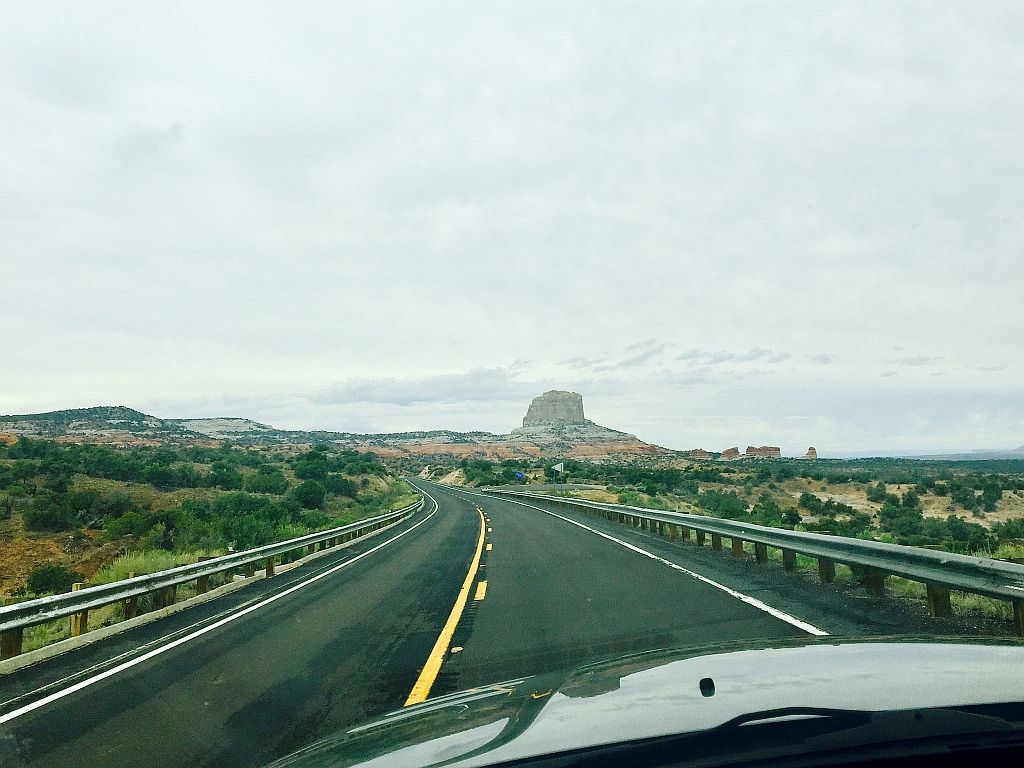 A car is driving down a highway with a mountain in the background