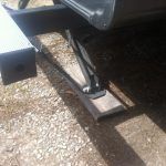 A close up of the underside of a car with a trailer attached to it.