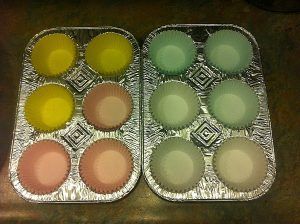 Two aluminum foil trays filled with cupcake liners of different colors