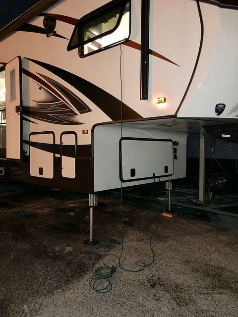 A white and brown rv is parked in a gravel lot
