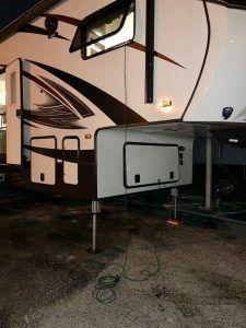 A white and brown rv is parked in a gravel lot.