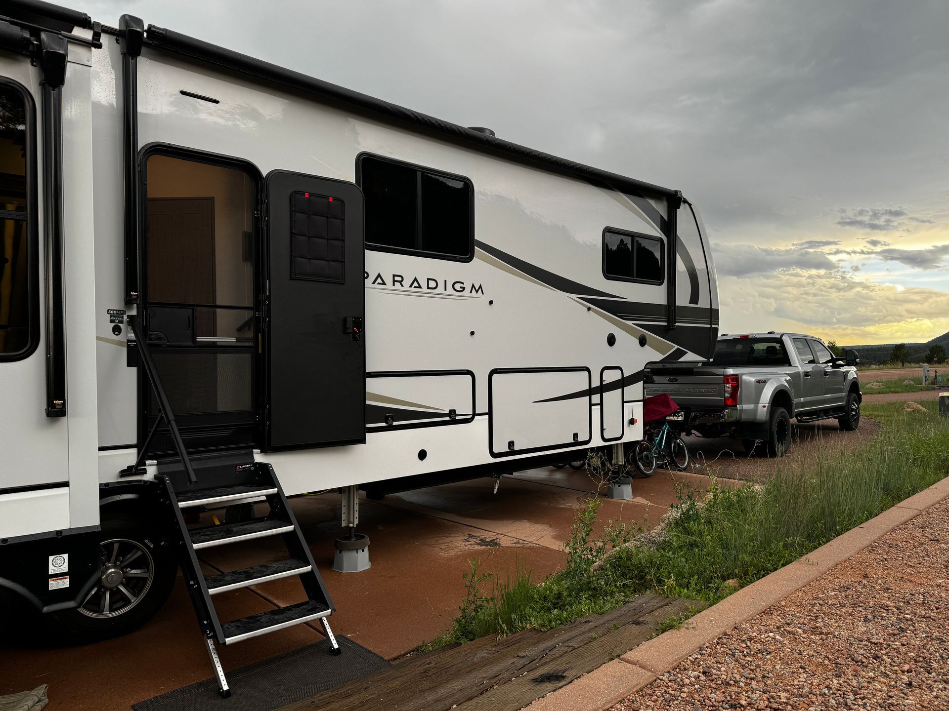 A white rv is parked in a parking lot next to a truck.