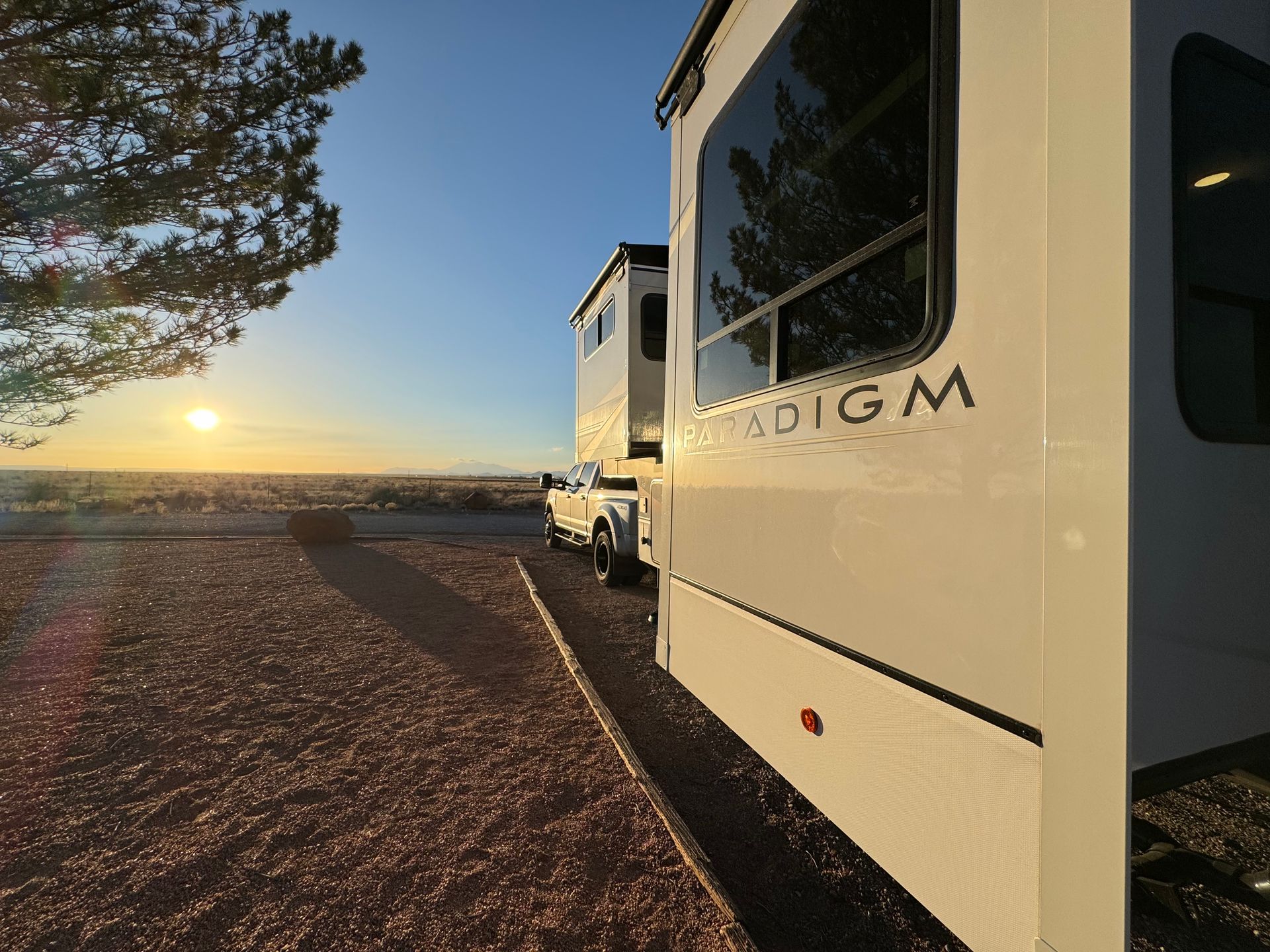 A white rv is parked on the side of the road at sunset.