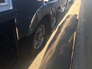 A truck is parked on the side of the road next to a wall.