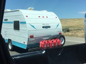 A white rv is parked on the side of the road next to a truck.