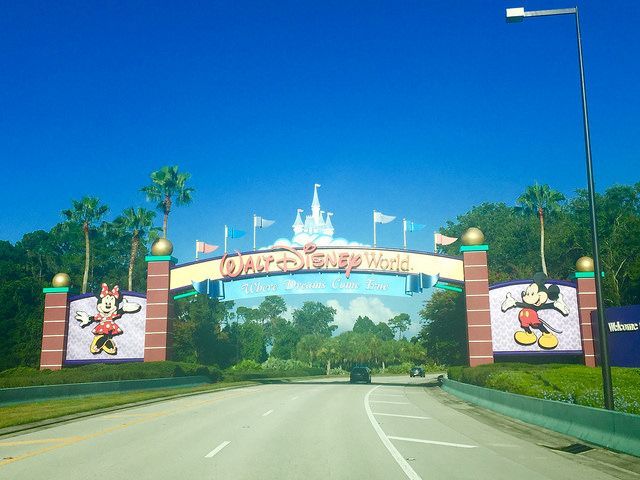 A car is driving past a disney world welcome sign.