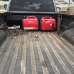 The back of a truck with two red generators in the bed.