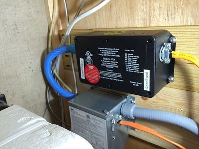 A black box with a red sticker on it is sitting on a wooden wall.