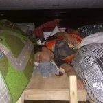 A young boy is sleeping under a bed.
