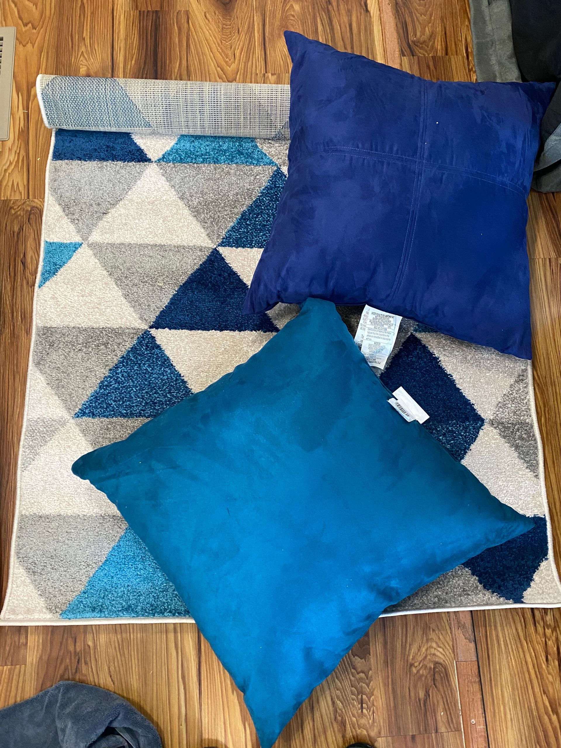 Blue and turquoise pillows on a geometric patterned rug.