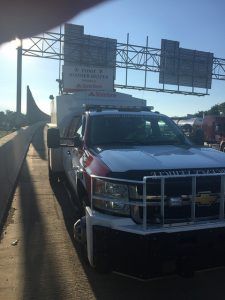 A white truck is parked on the side of a highway.