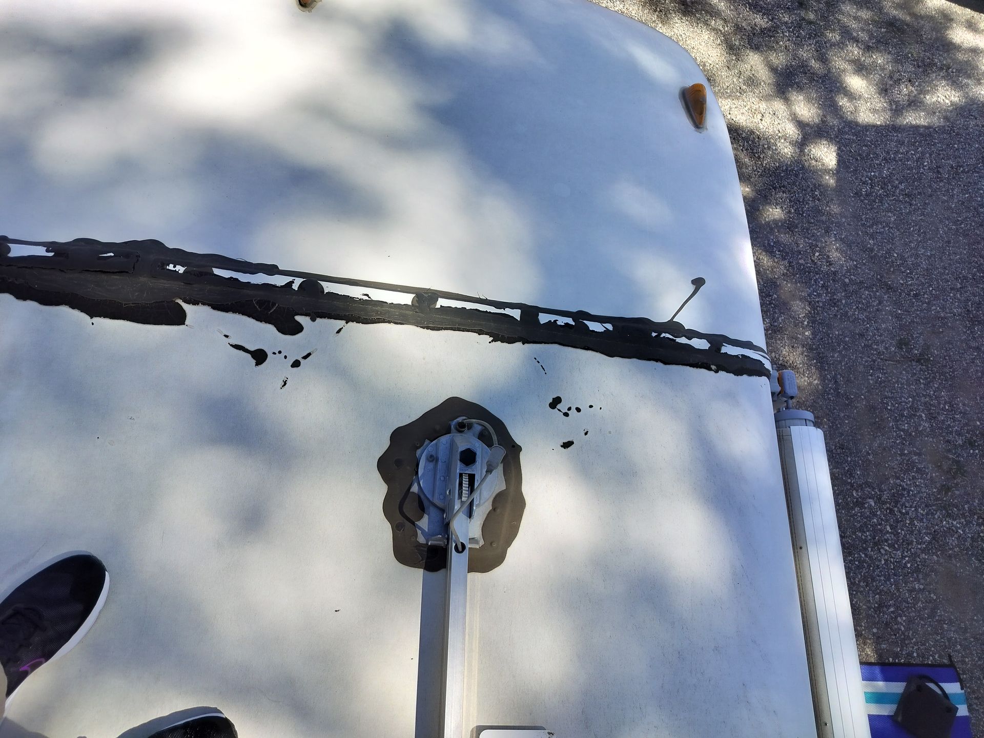 Close-up of a white vehicle hood with a central latch and a dark horizontal crack or seam.