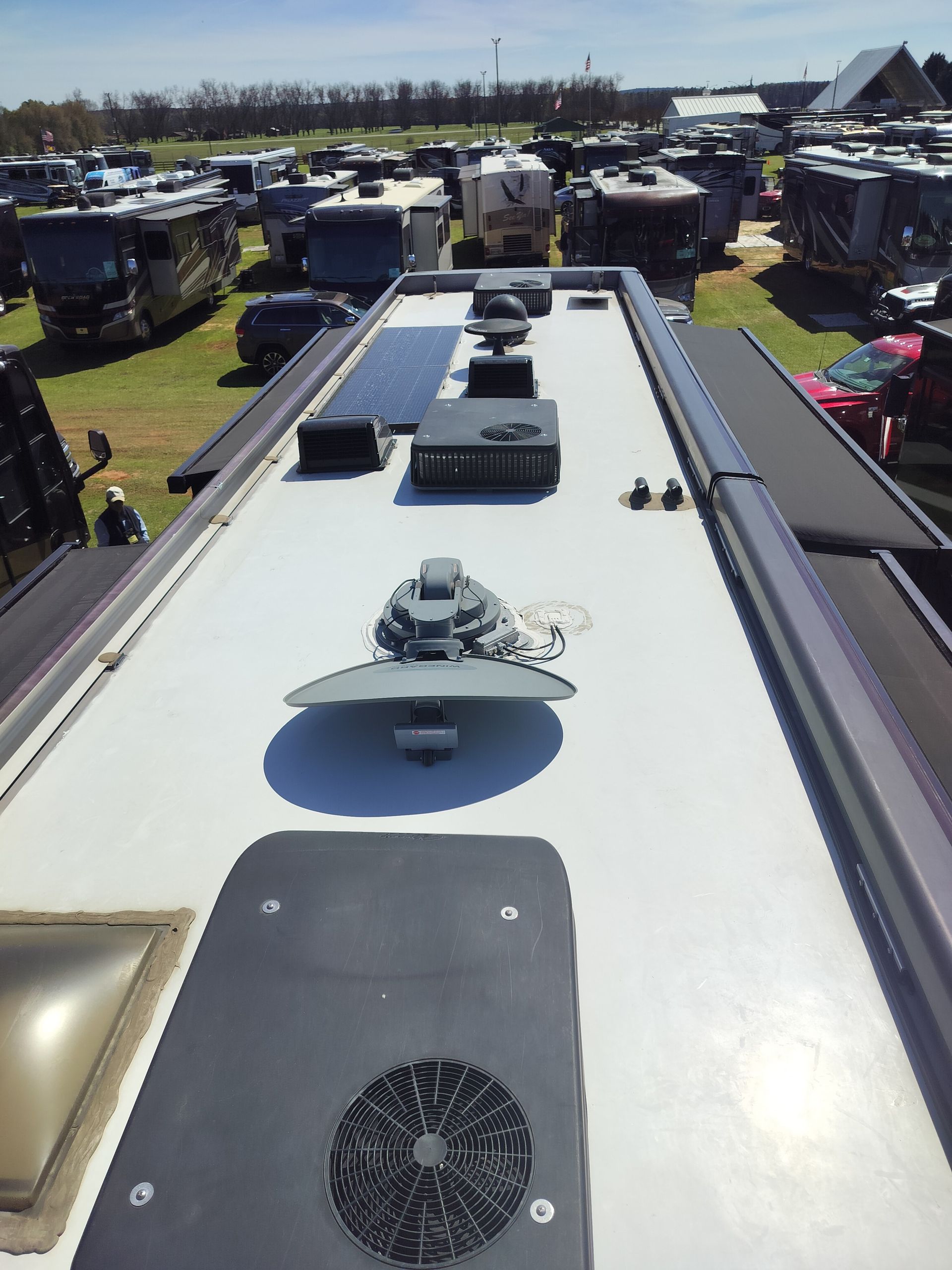View from RV roof with solar panel, vents, and roof fan at an outdoor RV show