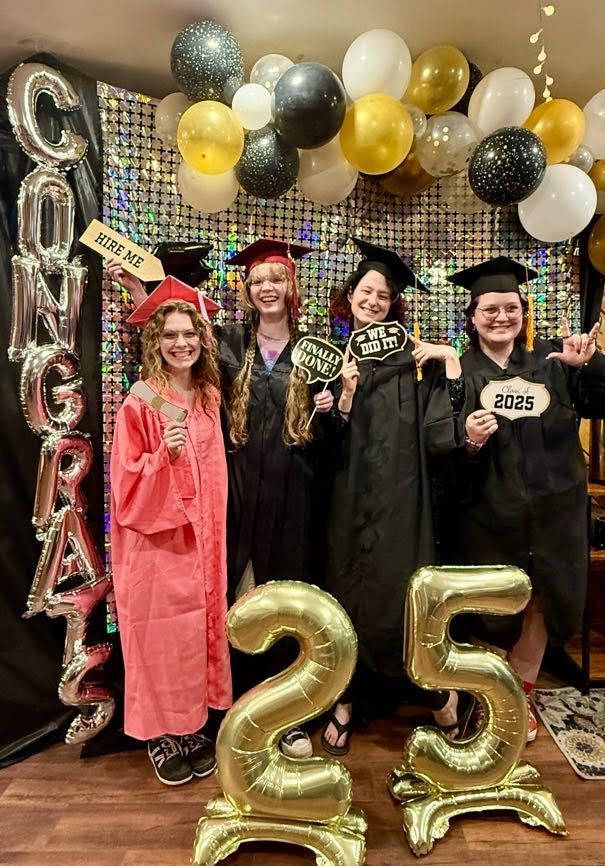 A group of graduates are posing for a picture with balloons.