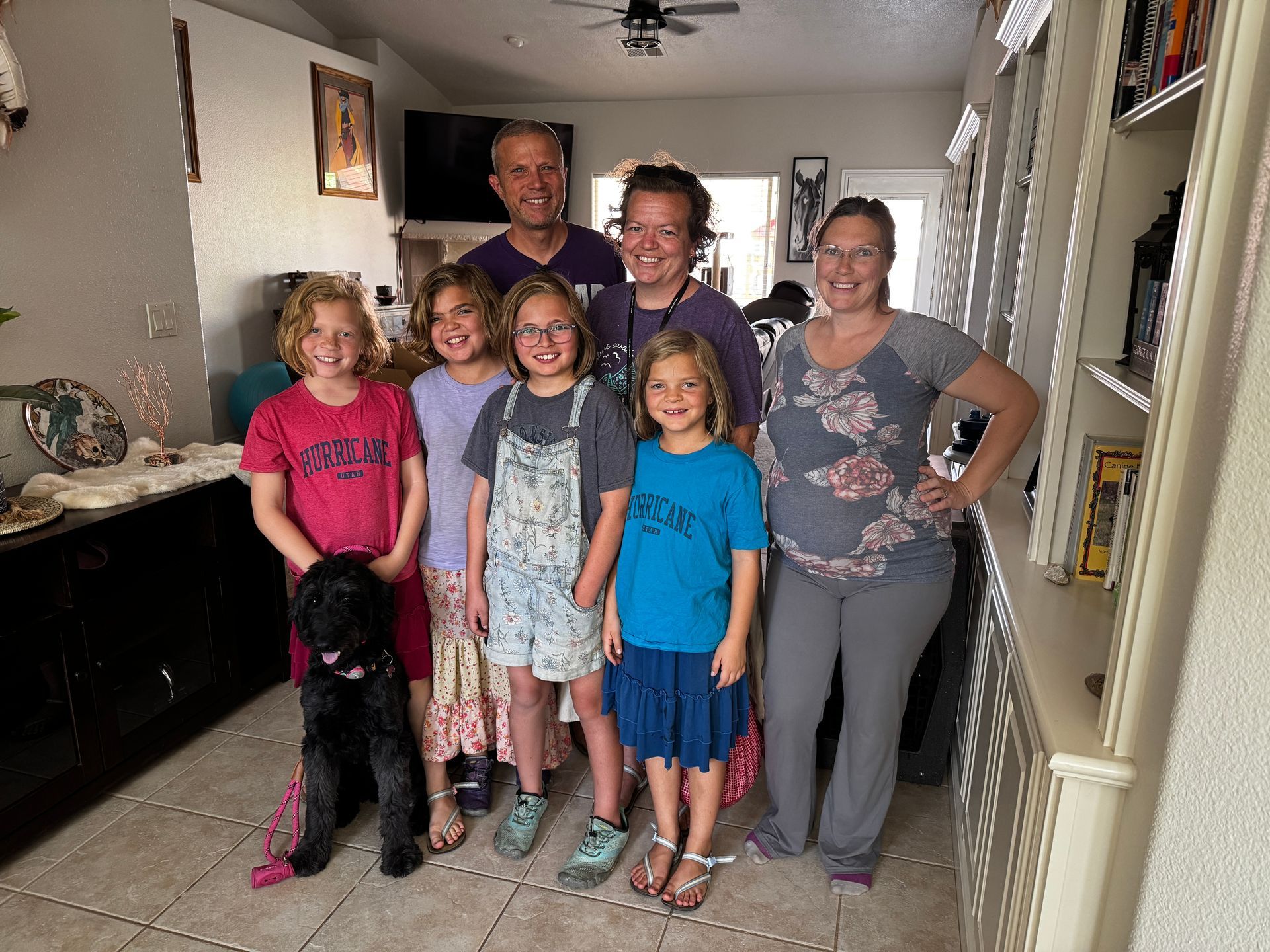 A family posing for a picture in a living room with a dog.