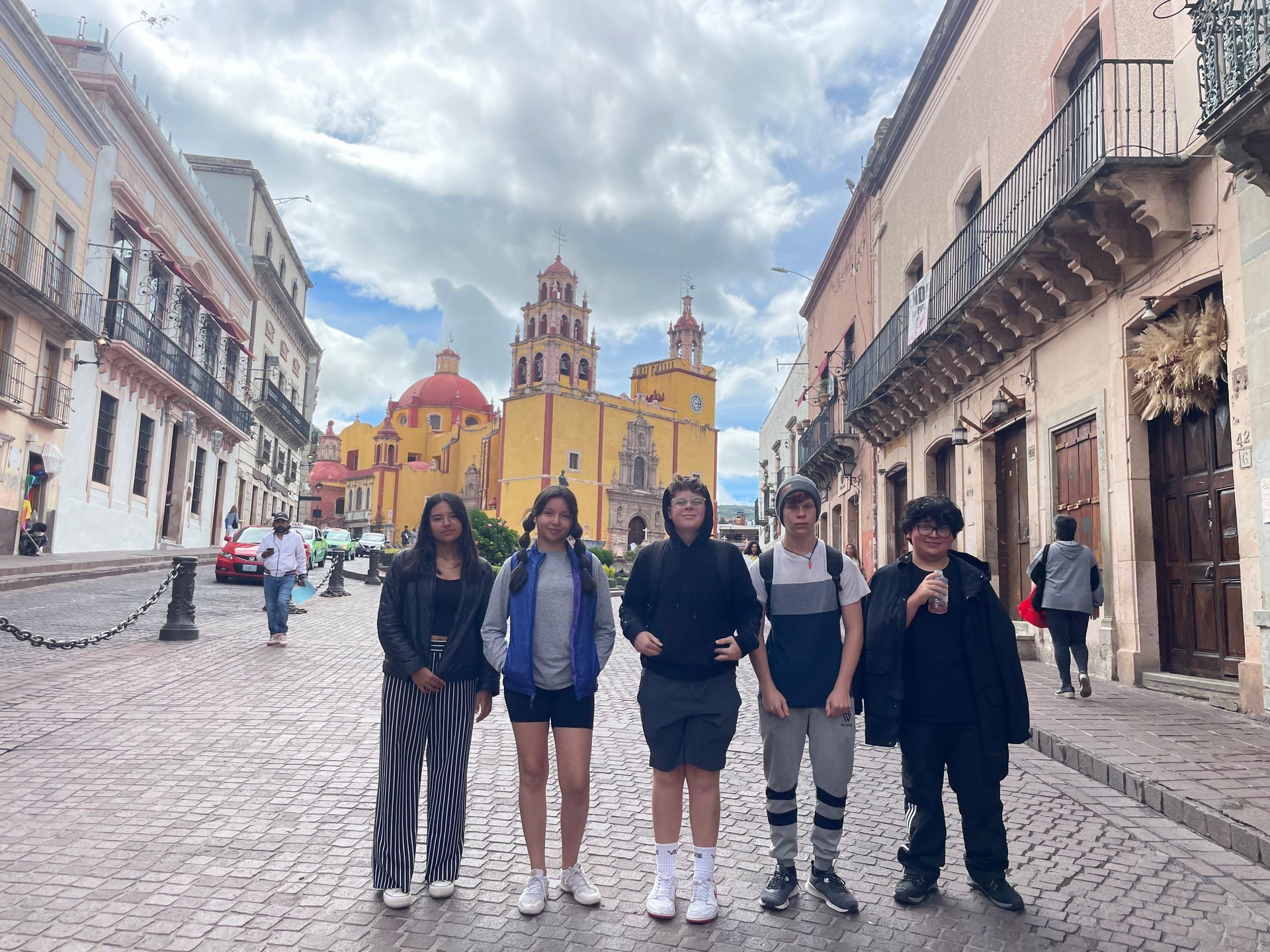 A group of people are standing on a cobblestone street in front of a building.
