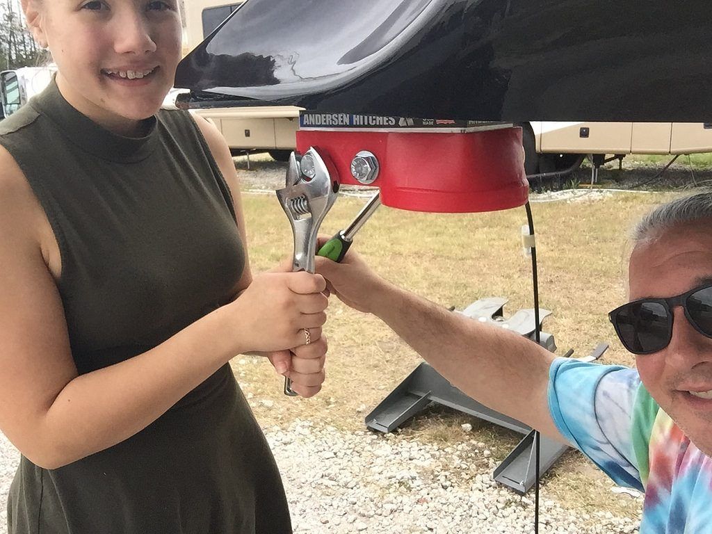 A woman is holding a wrench next to a man wearing sunglasses.