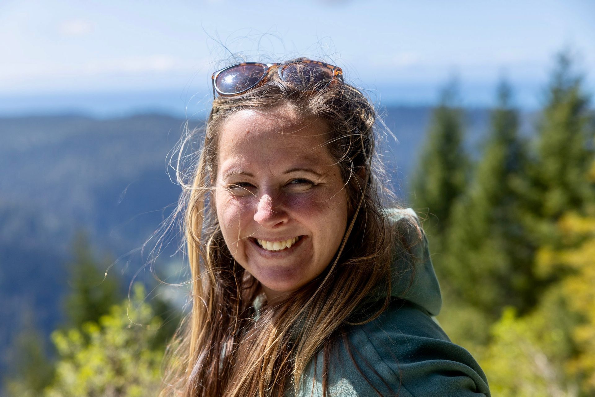 Woman with sunglasses smiles; light hair, fair skin...