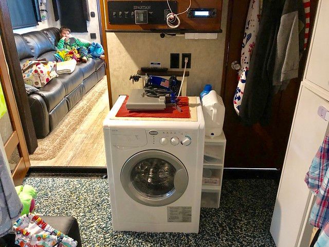 A washer and dryer are in a laundry room next to a couch.