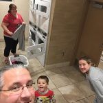 A man is taking a selfie with two children in a kitchen.