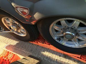 Gray vehicle tires on orange leveling blocks on a concrete surface.
