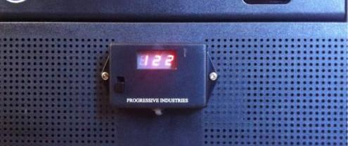 Digital voltage display reading 122, mounted on a dark surface with small holes. 