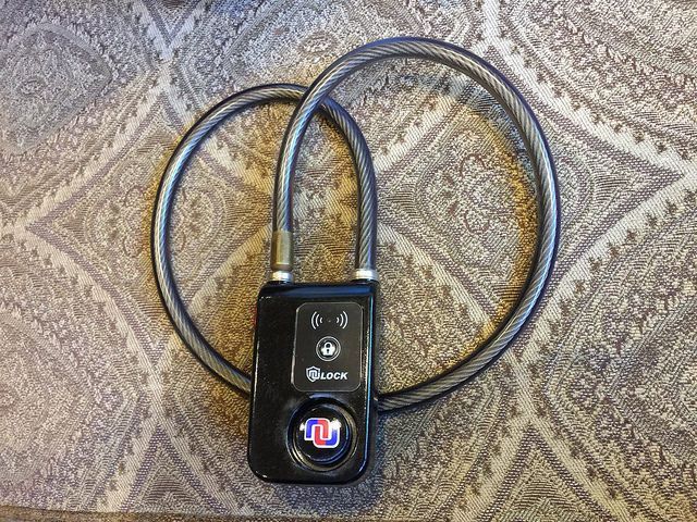 A black device with a remote control is sitting on a carpet.