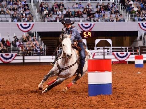 A man is riding a horse around a barrel at a rodeo.
