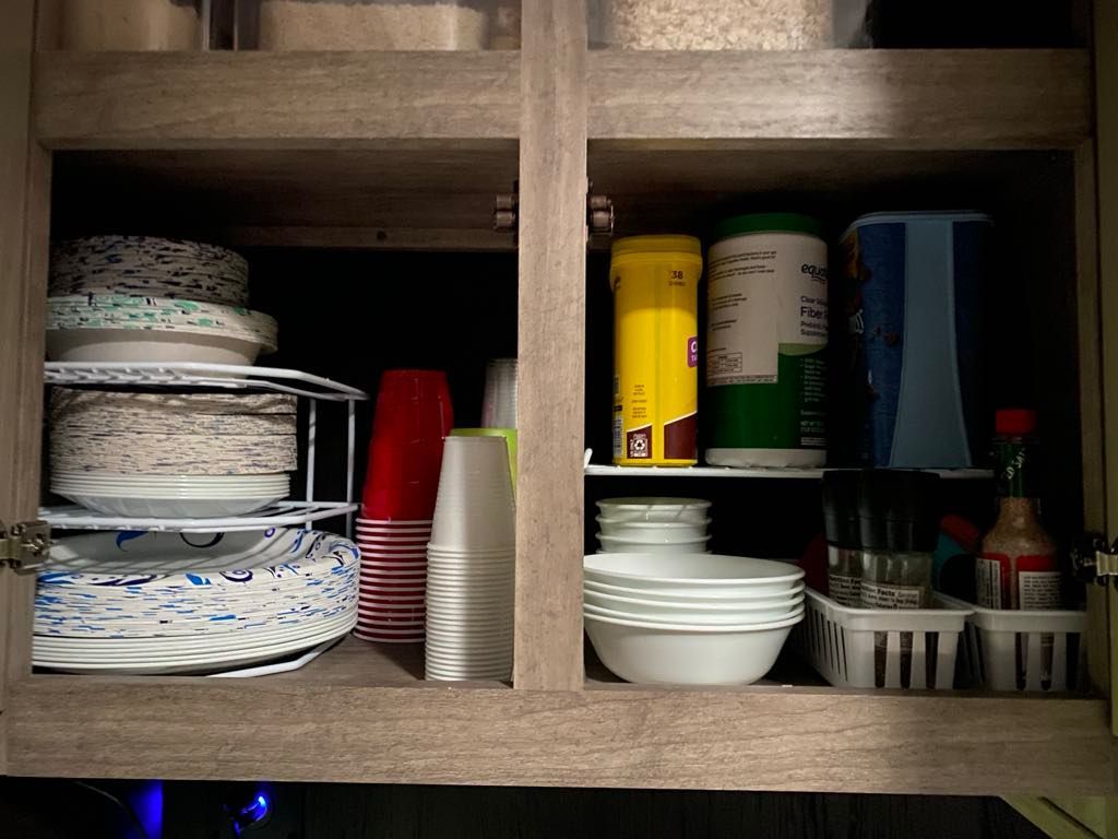 Cabinet with stacked plates, cups, bowls, and containers of various sizes and colors.
