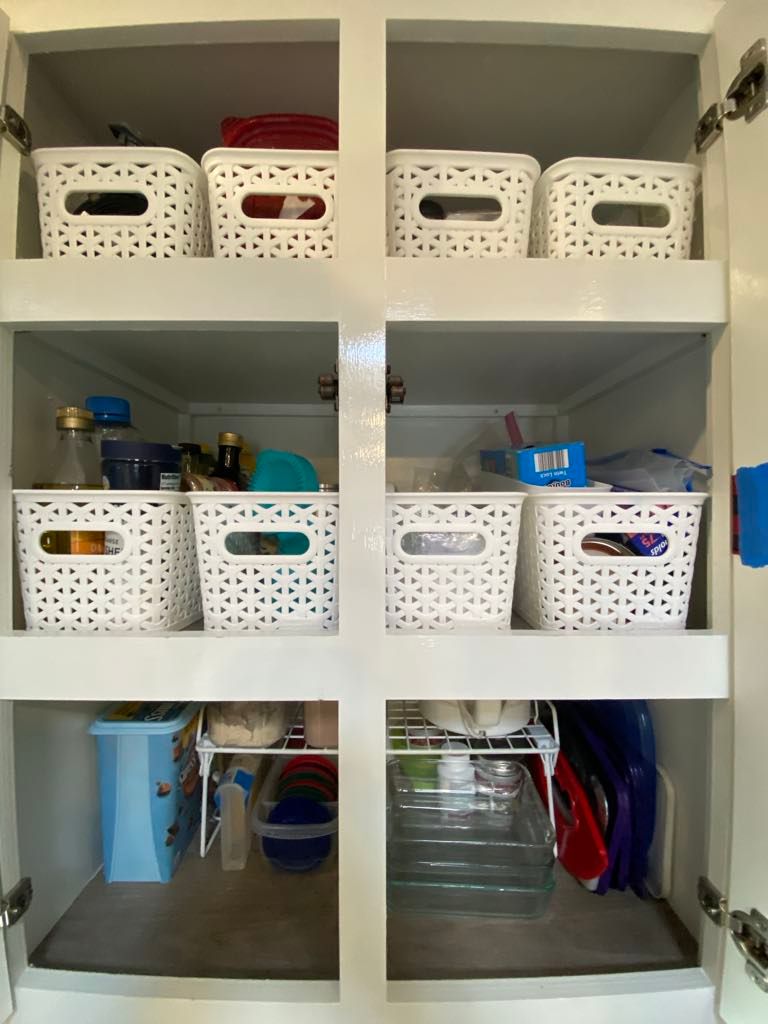 White kitchen cabinet with organized storage containers.