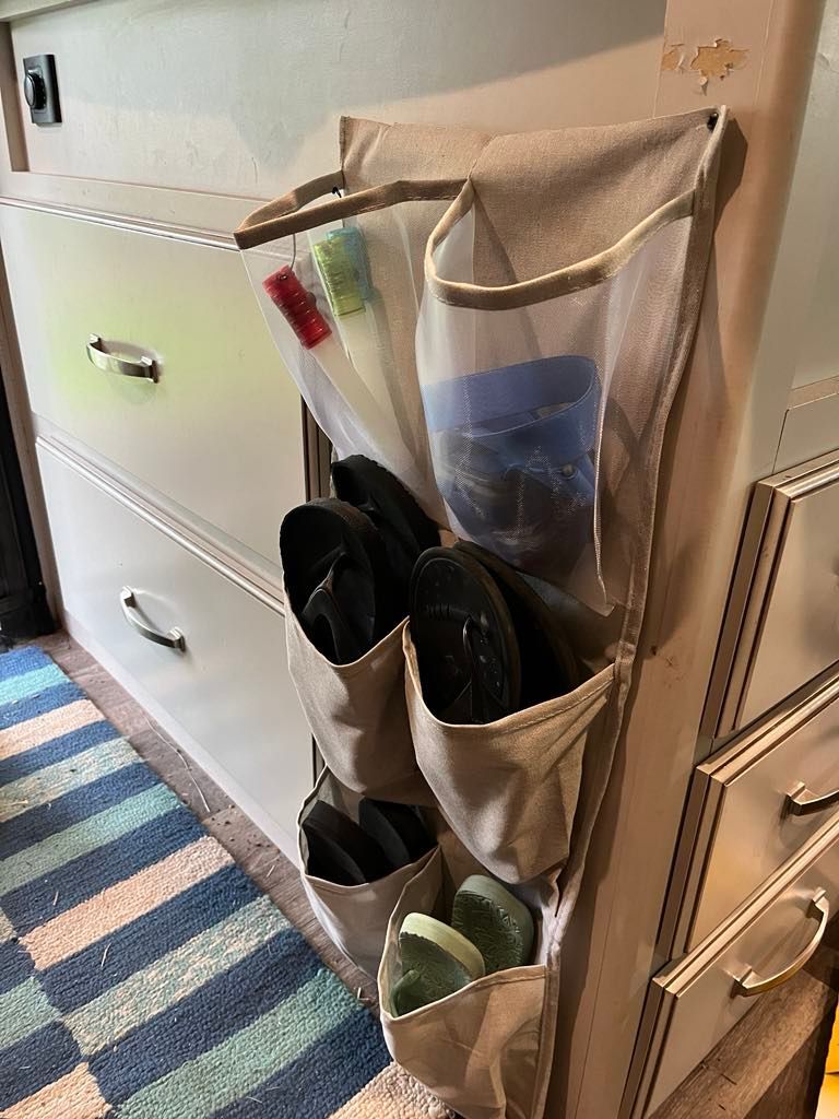 Shoe organizer hanging on a cabinet; holds flip-flops and other small items, in a room.