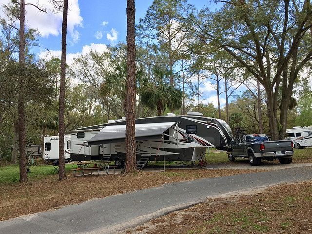 A truck is parked next to a rv in a campground.