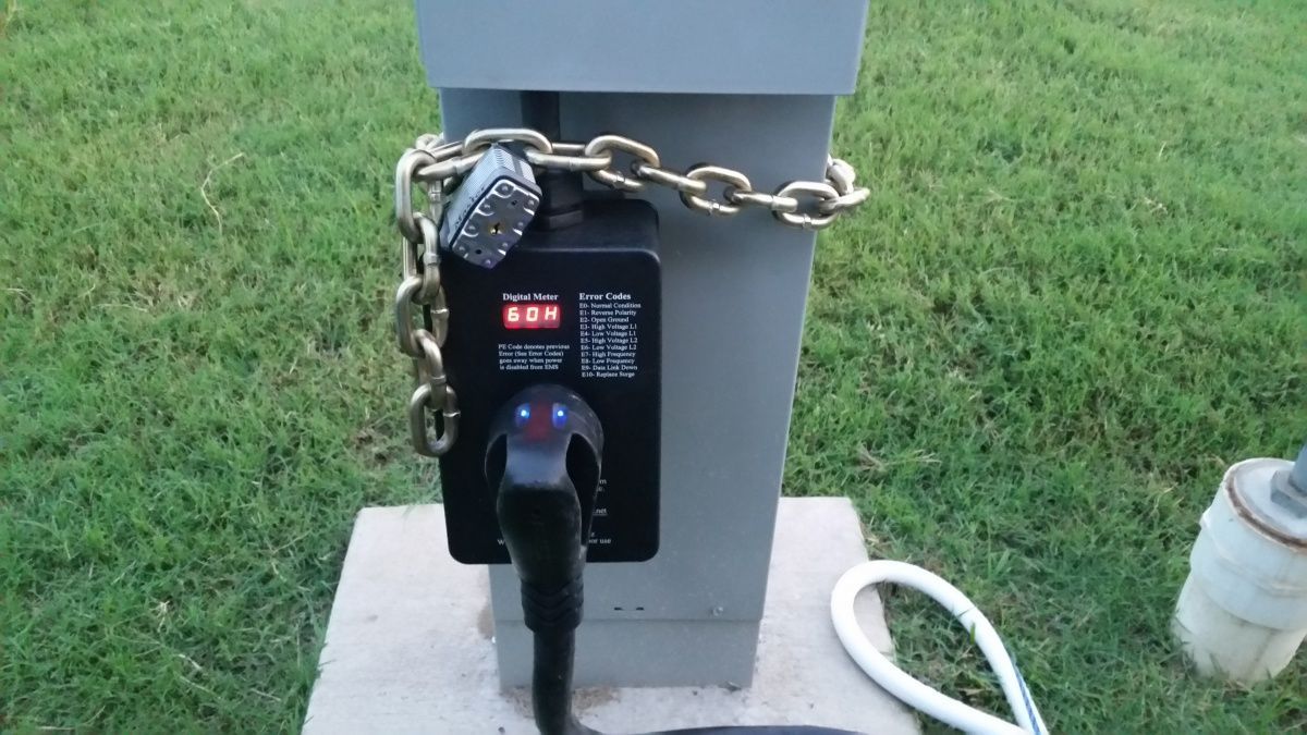 A telephone is chained to a pole with a padlock.